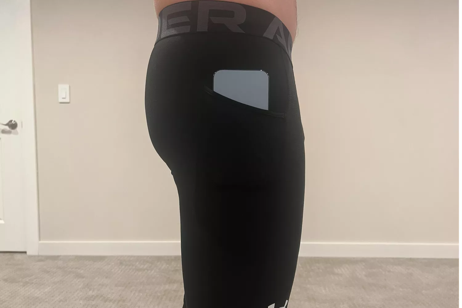 Rear view of running tights showing a smartphone securely tucked into a side hip pocket.