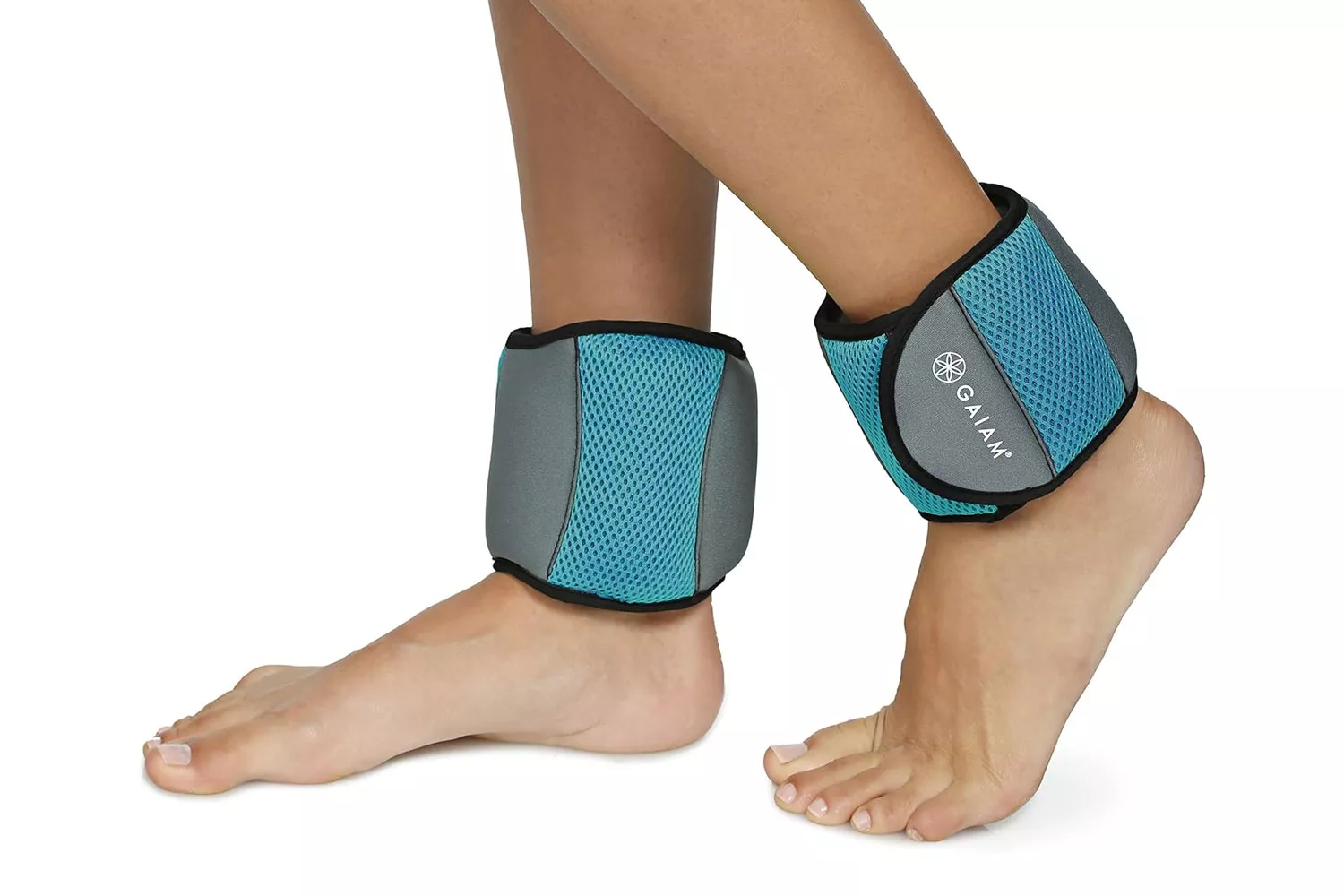A person standing and wearing Gaiam brand ankle weights on both ankles.