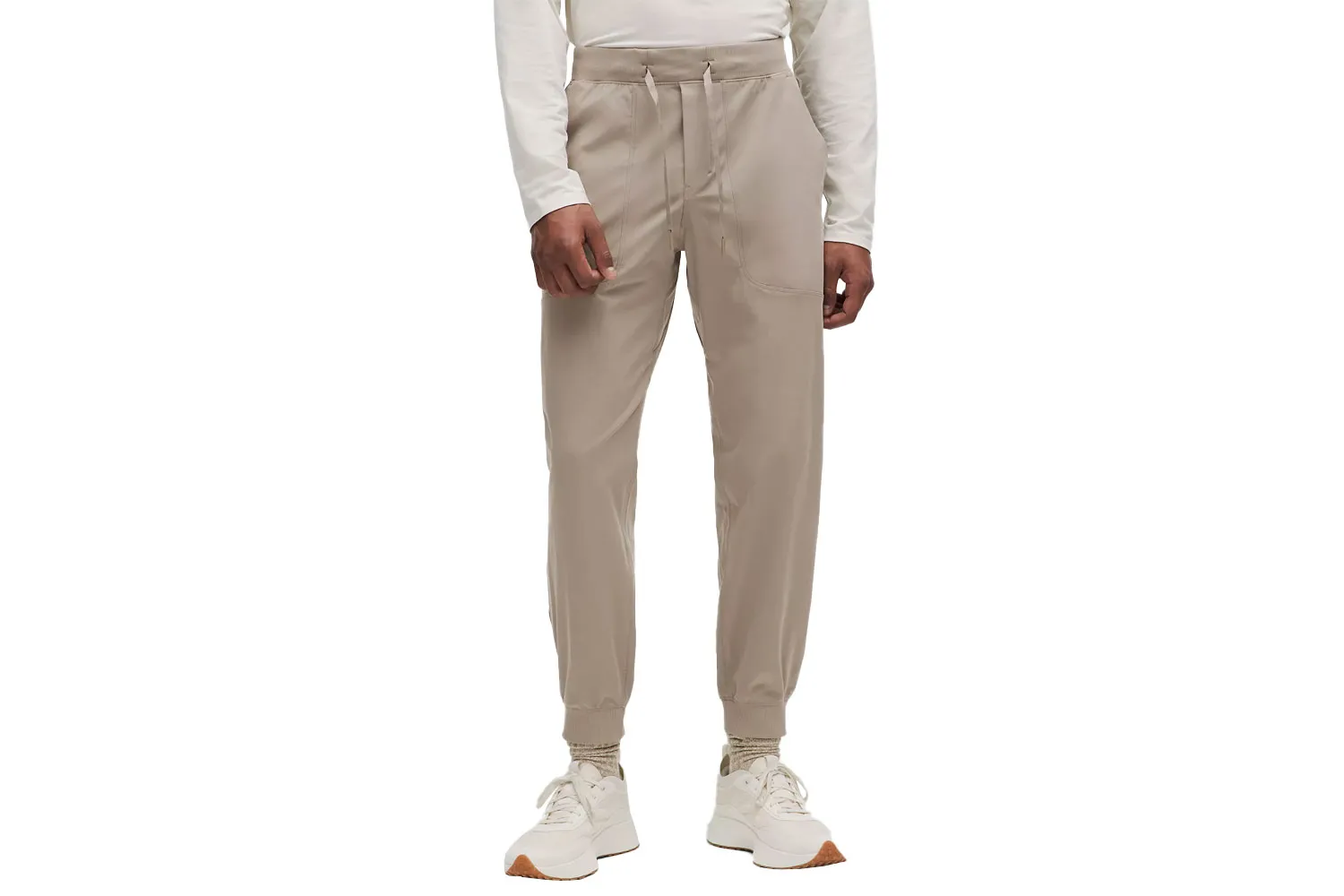 A male model wearing beige lululemon ABC Jogger pants against a neutral background.