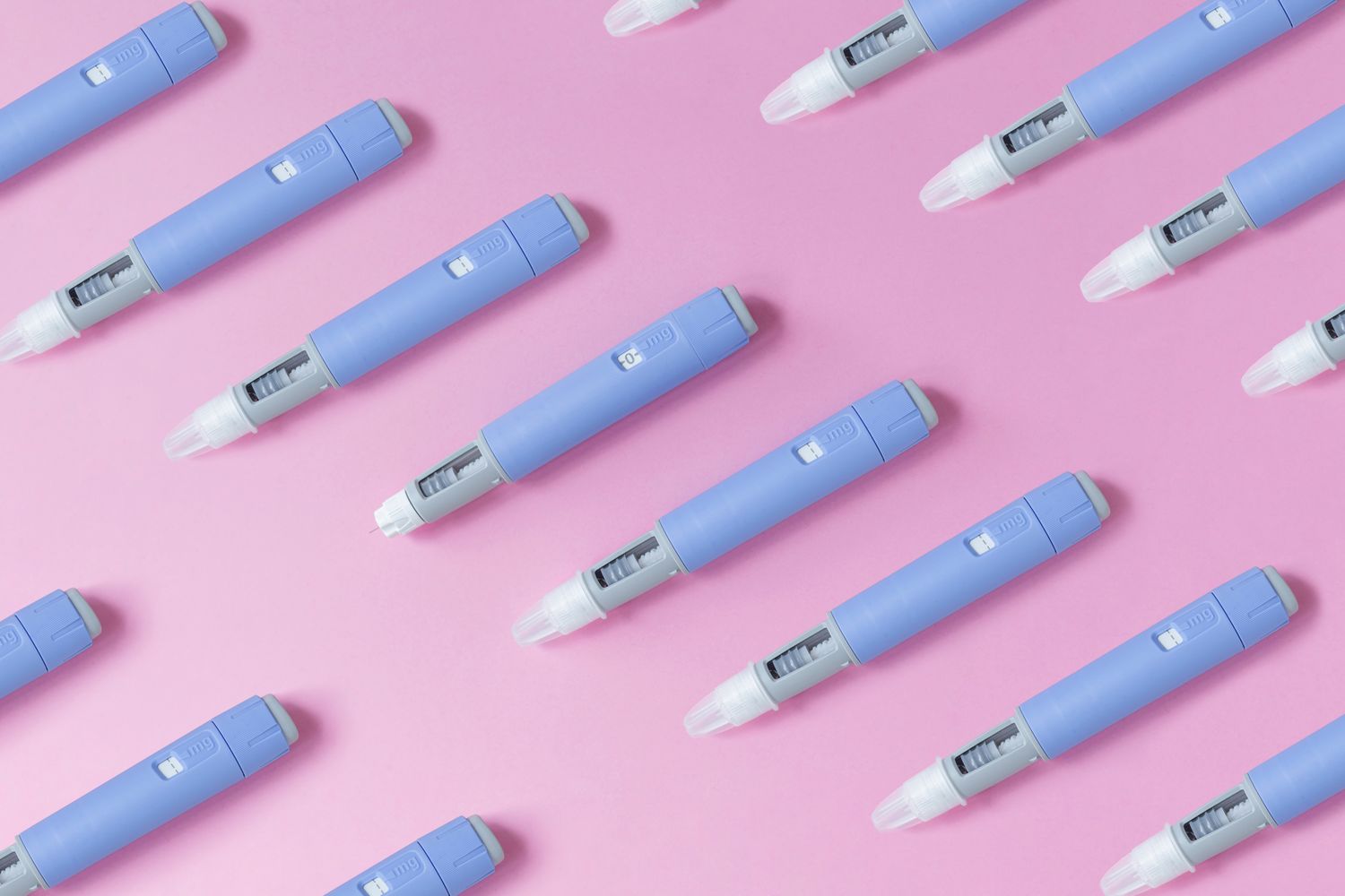 Multiple medical injector pens arranged in a pattern on a pink background.