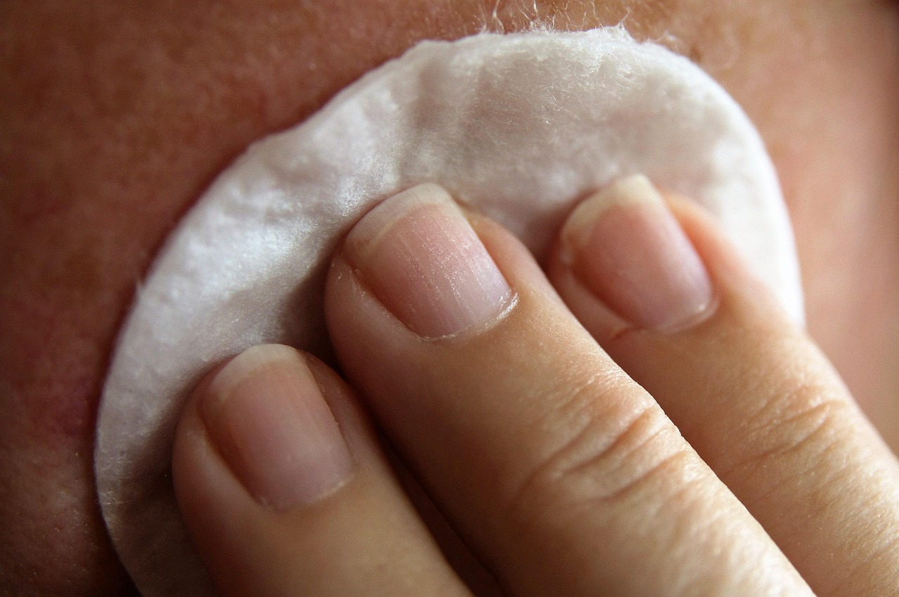 A close-up of a jade gua sha tool being used on a woman's neck for lymphatic drainage.