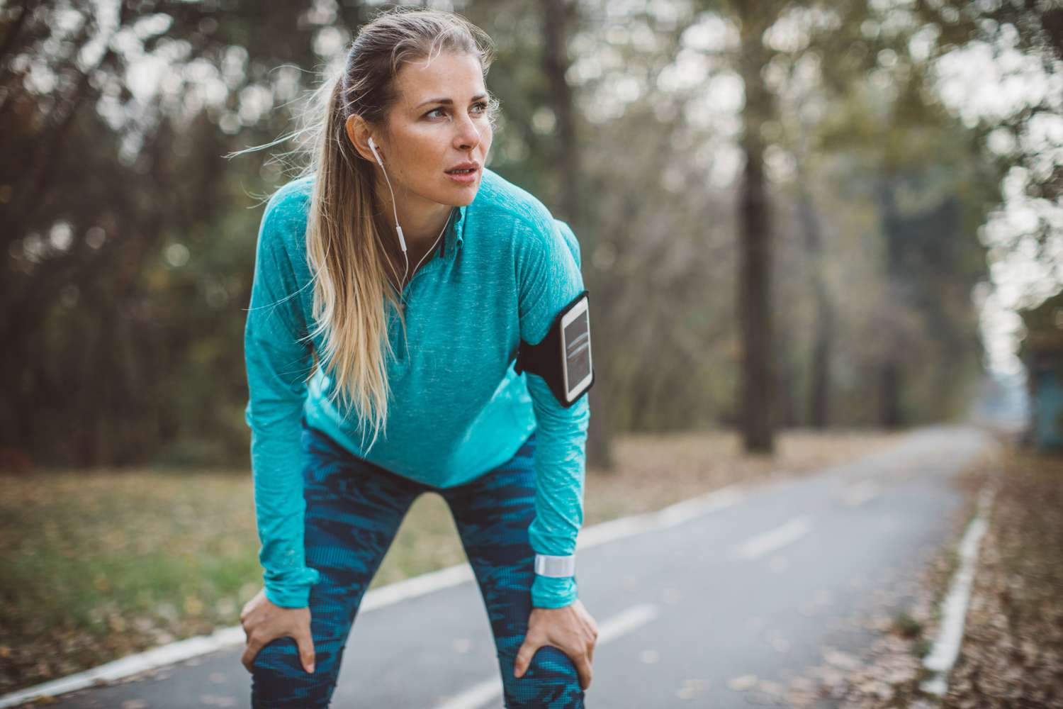 A runner taking a controlled break on a wooded trail to manage their heart rate.