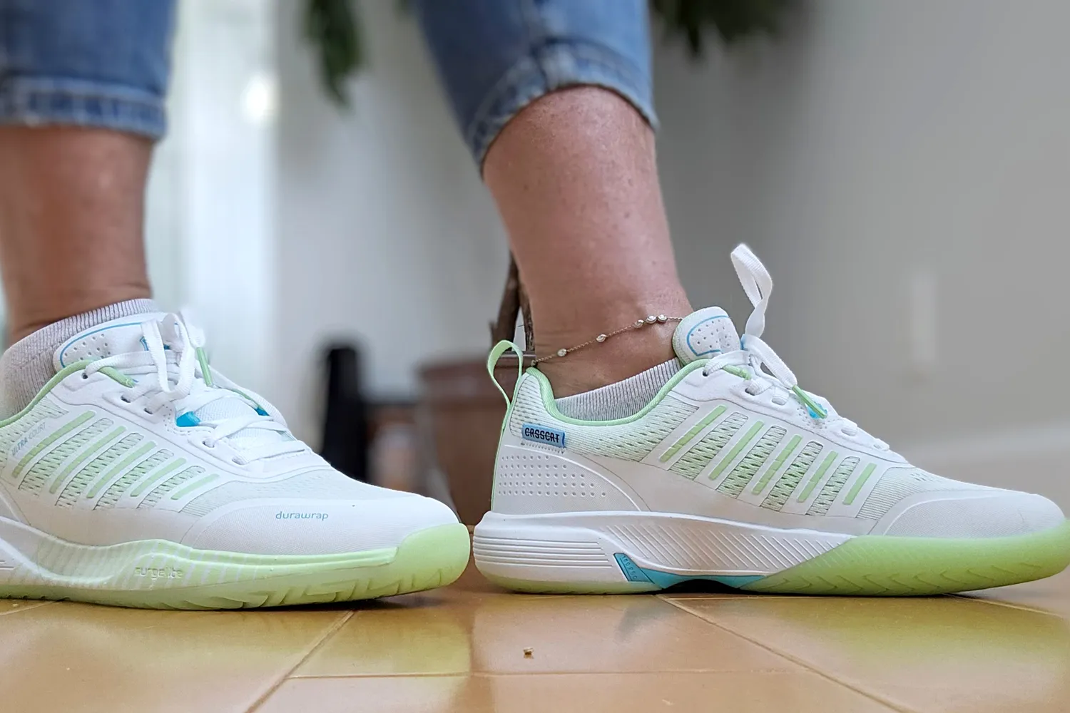 Side view of a white and green K-Swiss Ultra Court shoe worn indoors.