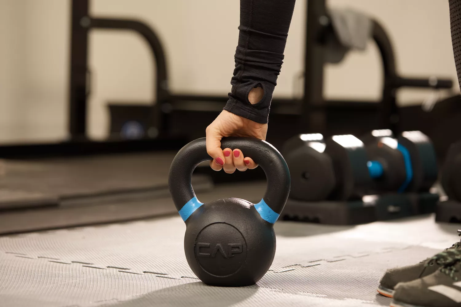 Close-up of a hand gripping a CAP kettlebell handle during a workout session.