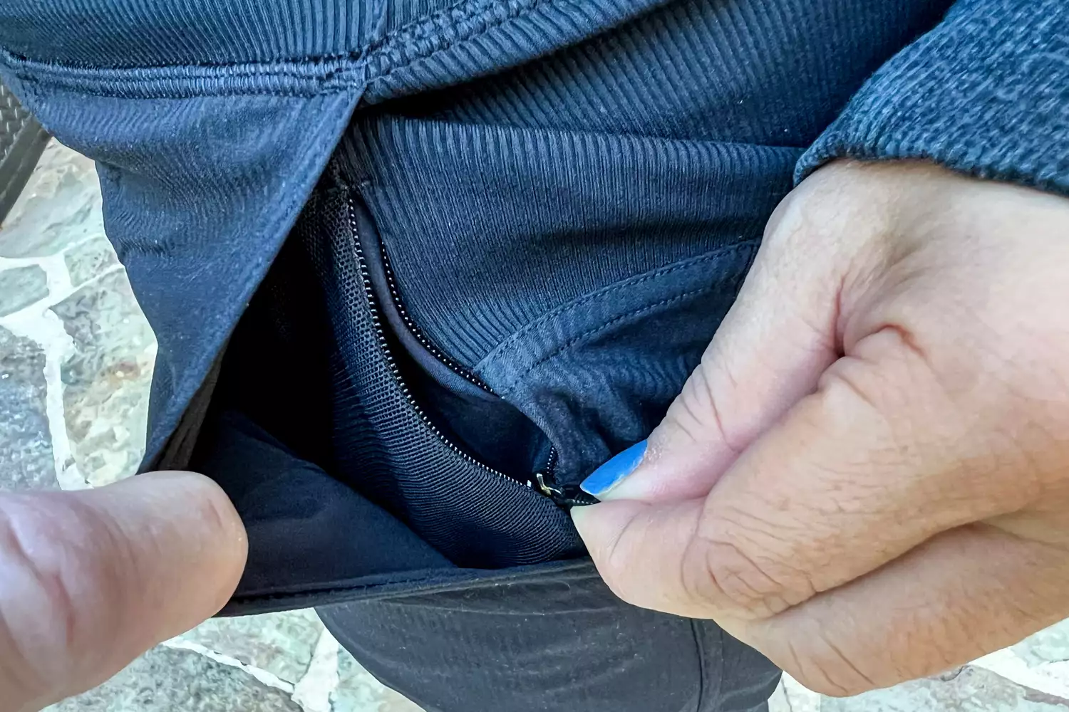Close-up of a person zipping up a pocket on dark lululemon athletic joggers.