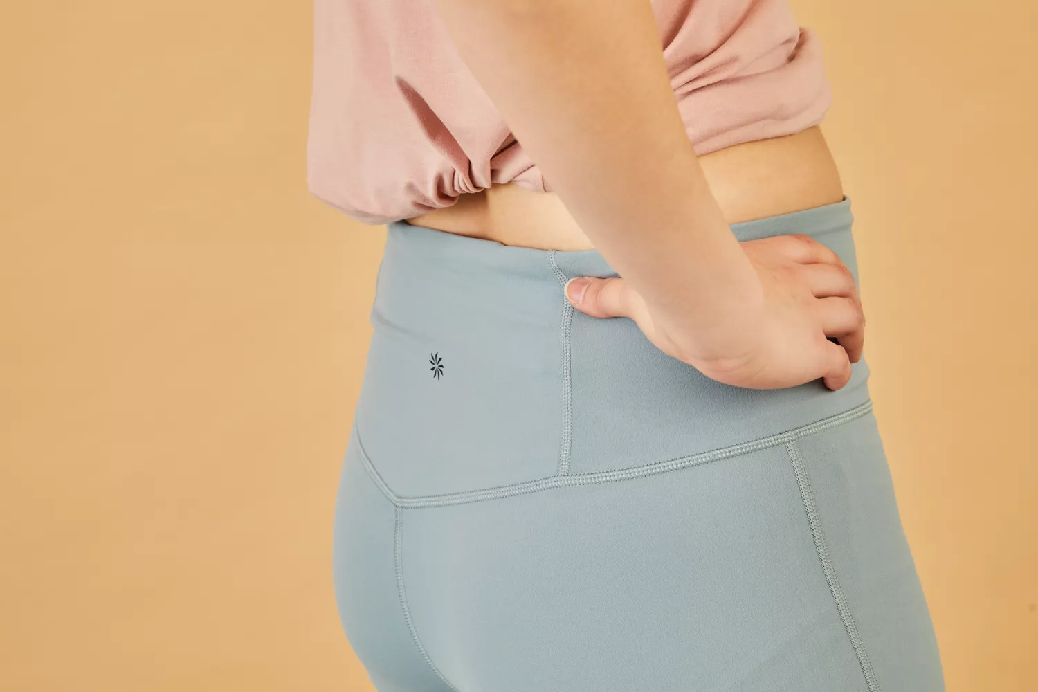 Close-up of a person wearing light blue high-waisted leggings with a hand on their hip.