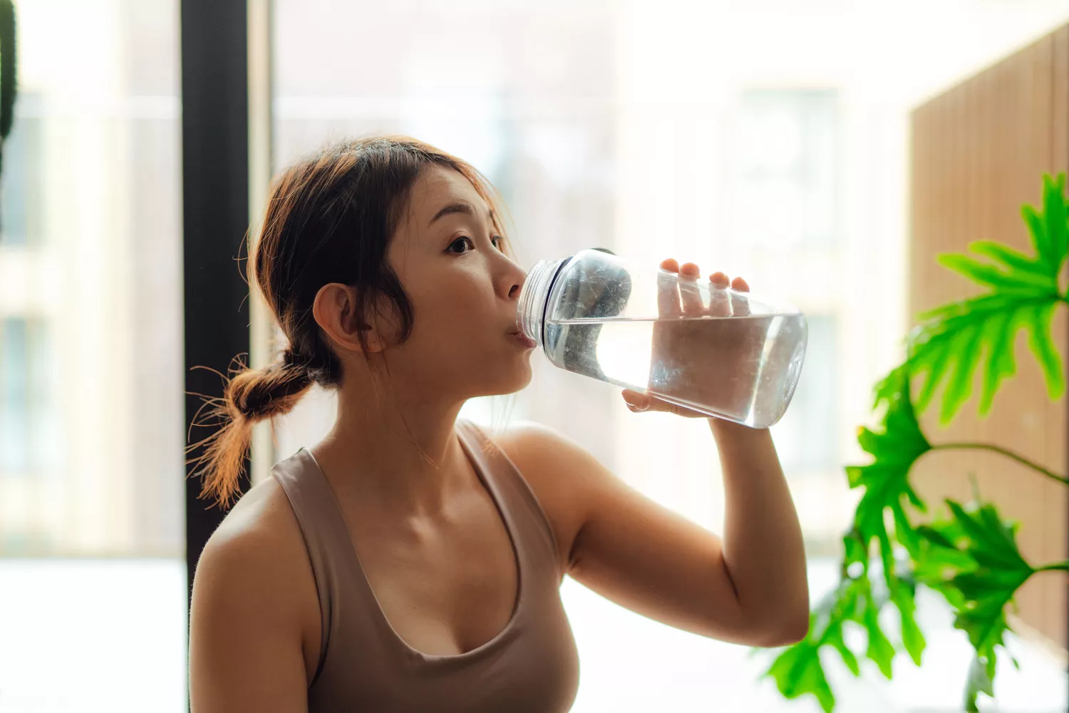 A woman drinking water from a clear glass.