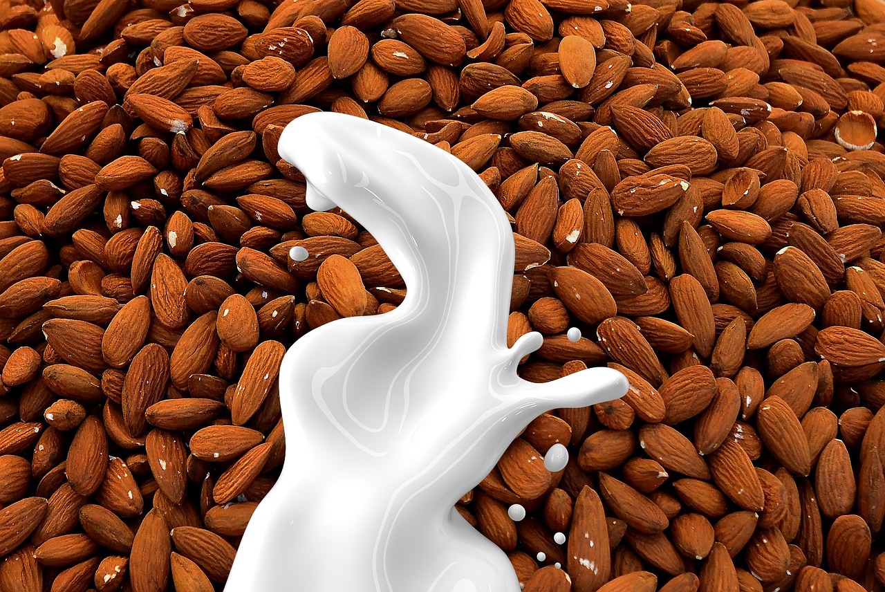 Flat lay of a coffee latte with a bottle of nut milk and a scoop of white powder