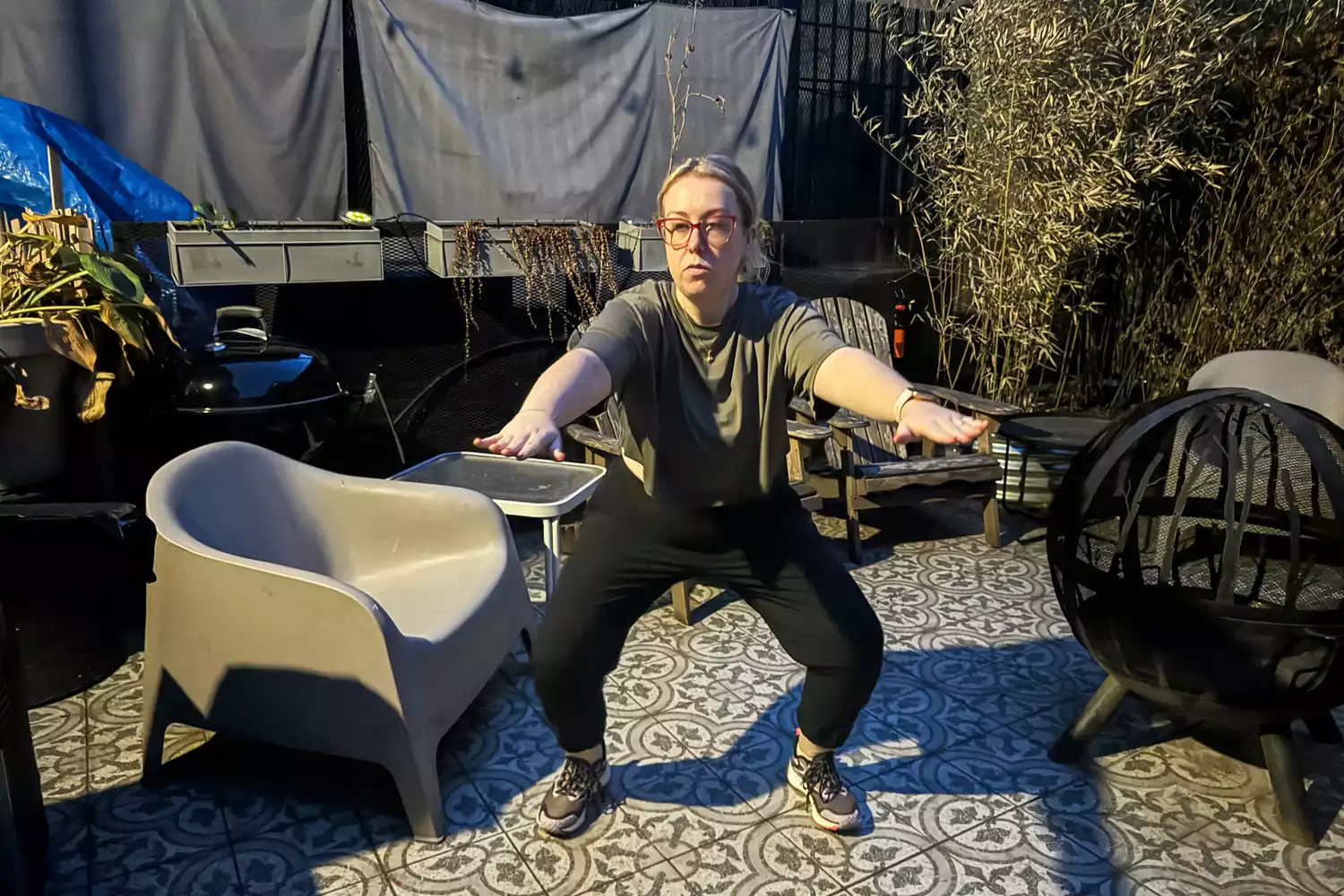 A woman performing a squat exercise outdoors wearing durable black joggers.