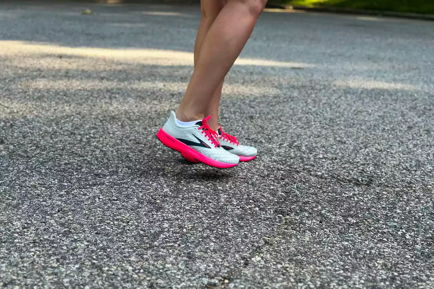 Action shot of a runner mid-stride wearing Brooks Hyperion performance shoes on the road.