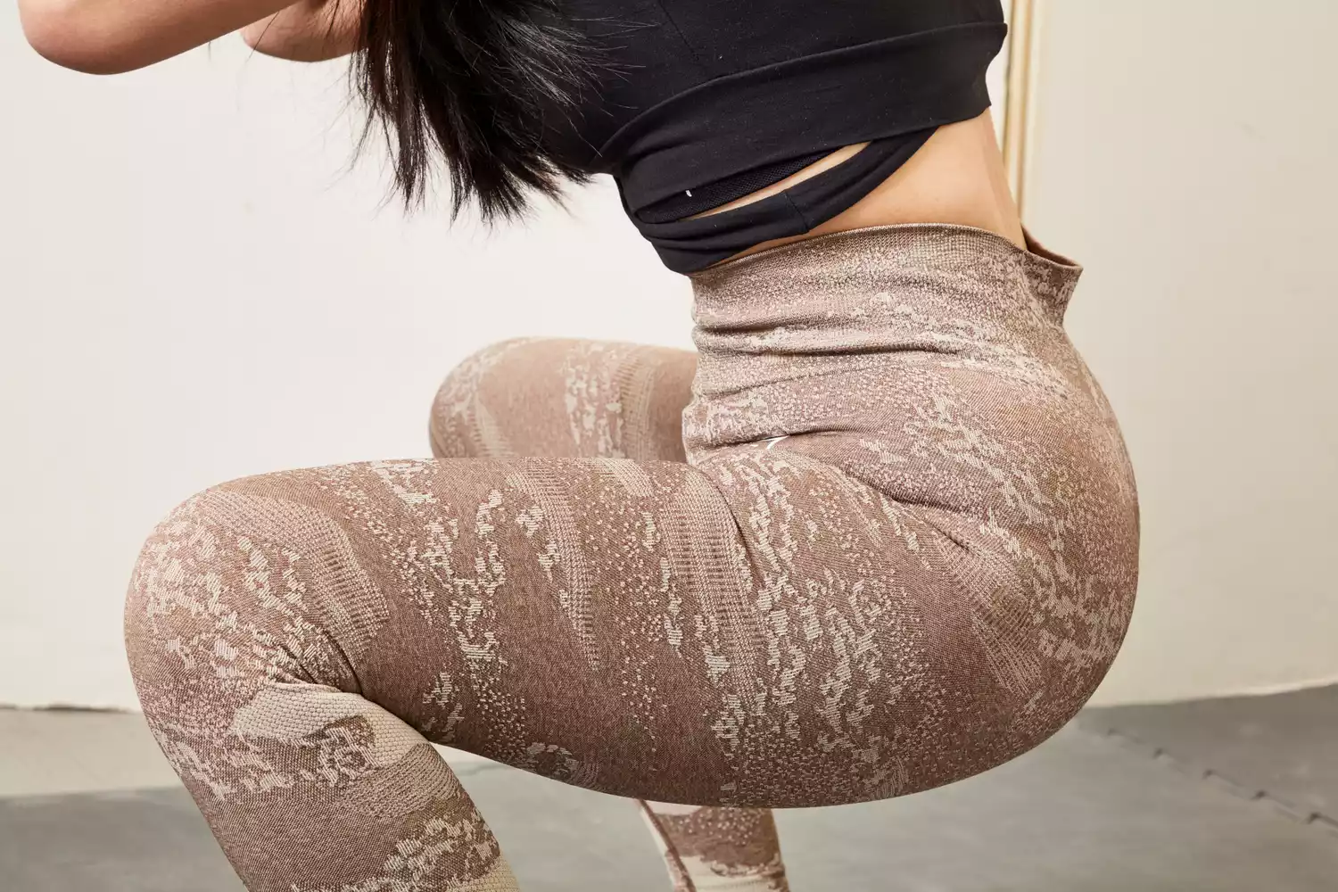 A woman in high-waisted camouflage leggings performing a deep squat in a gym.