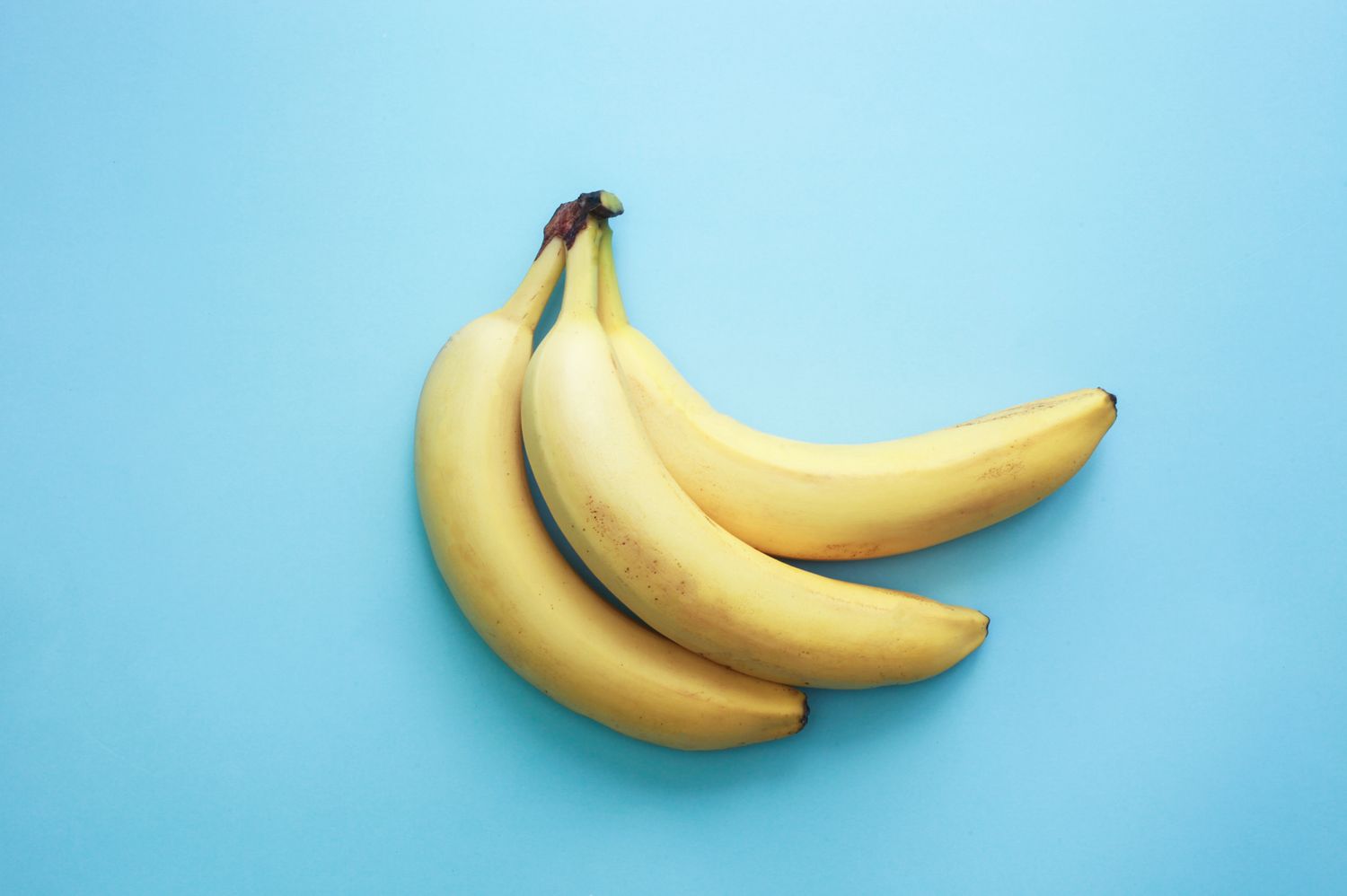Bright yellow bananas arranged on a clean blue background.