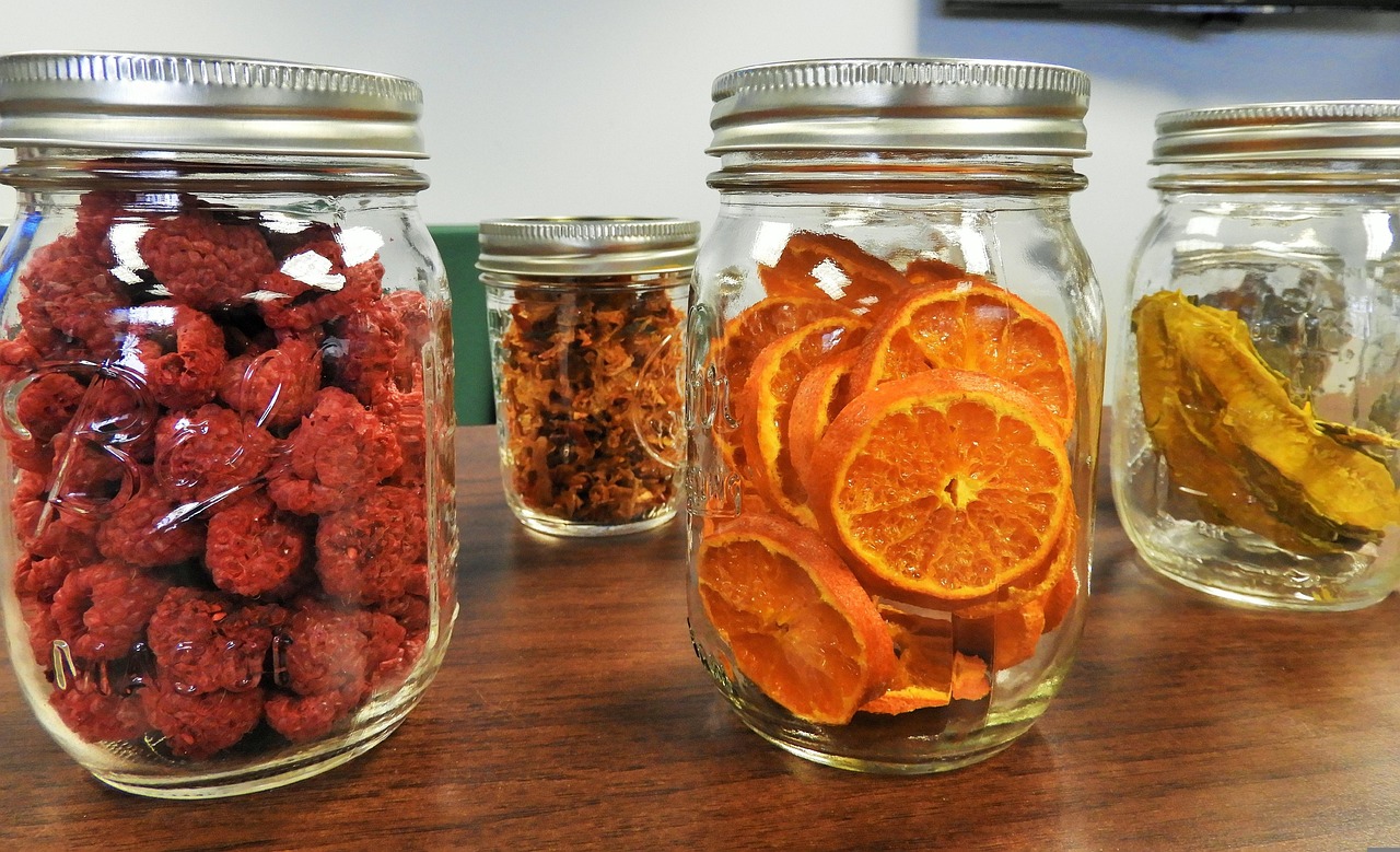 A clean glass mason jar next to a pile of organic seeds and a piece of cheesecloth.