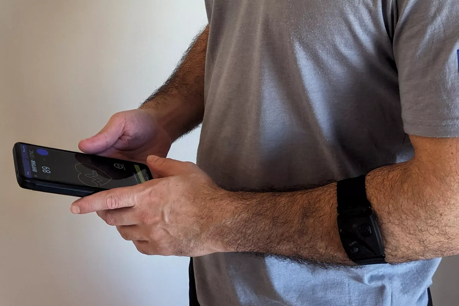 A person looking at a heart rate waveform and real-time BPM data on a smartphone fitness app.