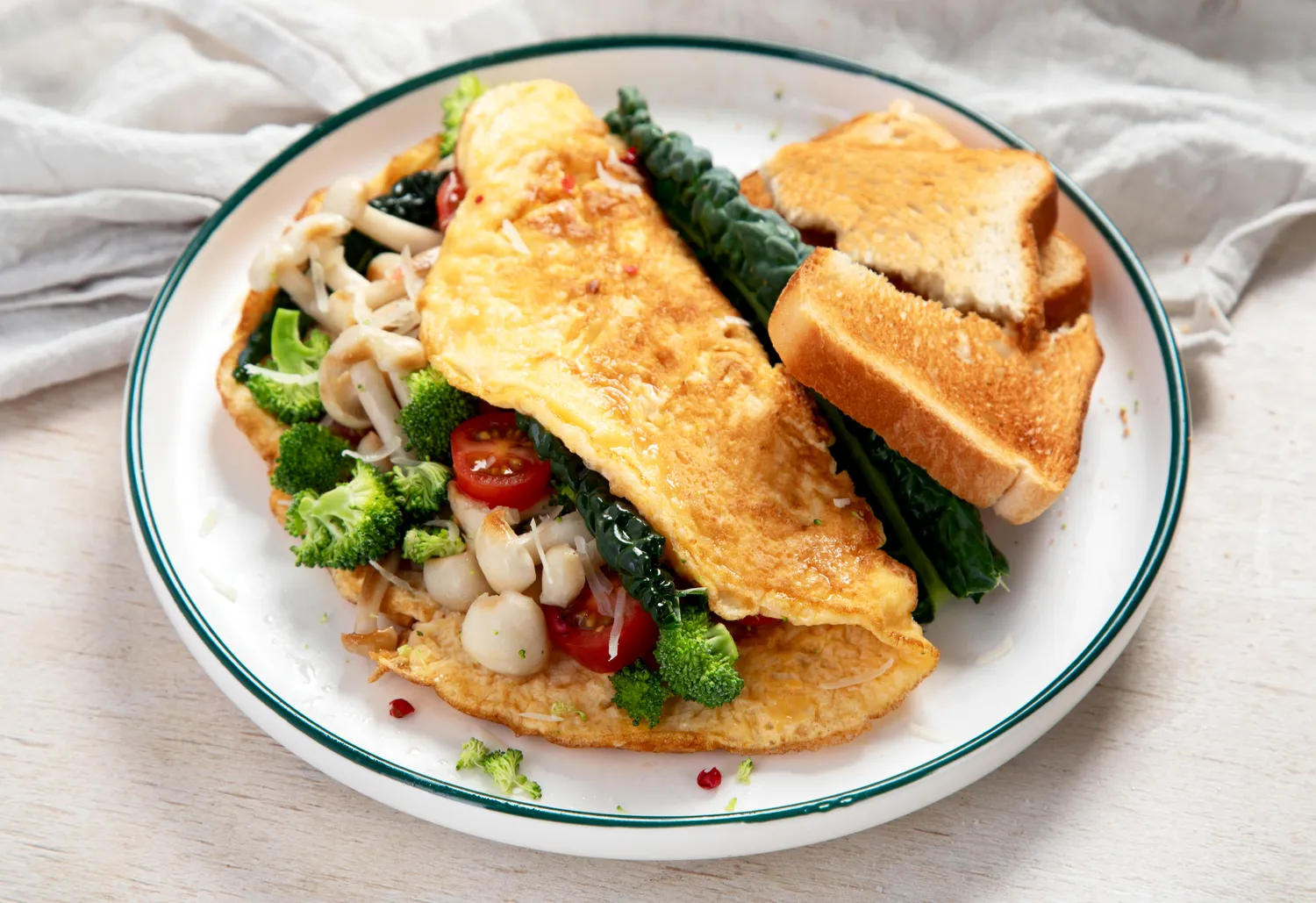 A veggie omelet with broccoli and mushrooms served with plain toast.