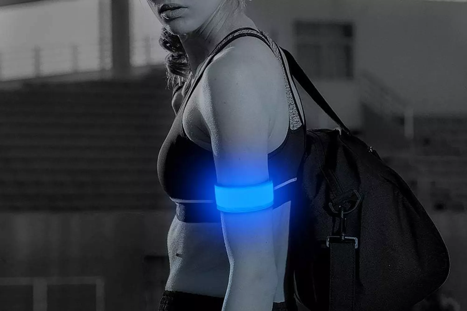 A female athlete wearing a blue LED armband during an evening workout.