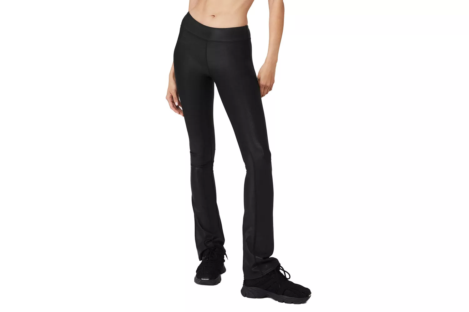 A model wearing black high-waisted flared leggings with a distinct shiny, compressive texture.