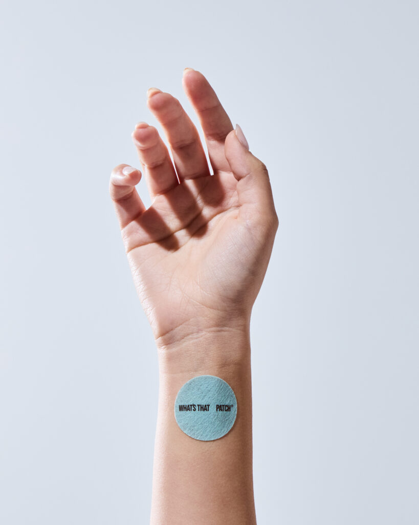 Close-up view of a square-shaped transdermal vitamin patch applied to a user's inner wrist.