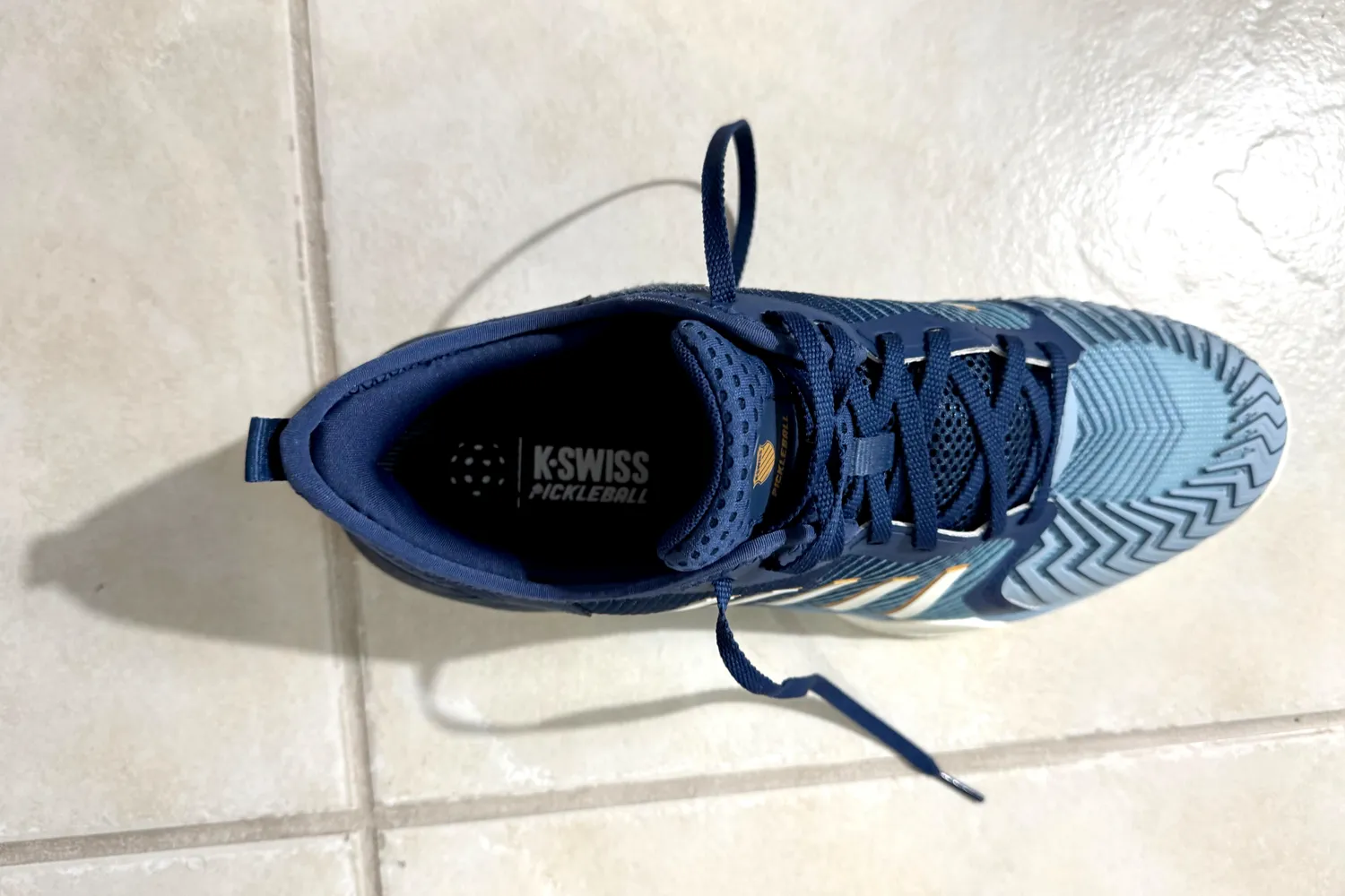 Overhead view of a K-Swiss Men's Pickleball Supreme shoe on a tiled floor.