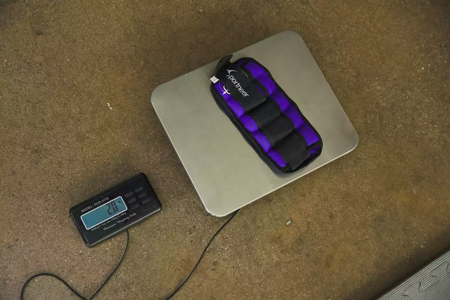 A purple Sportneer ankle weight being measured on a digital scale showing 2.0 lbs.