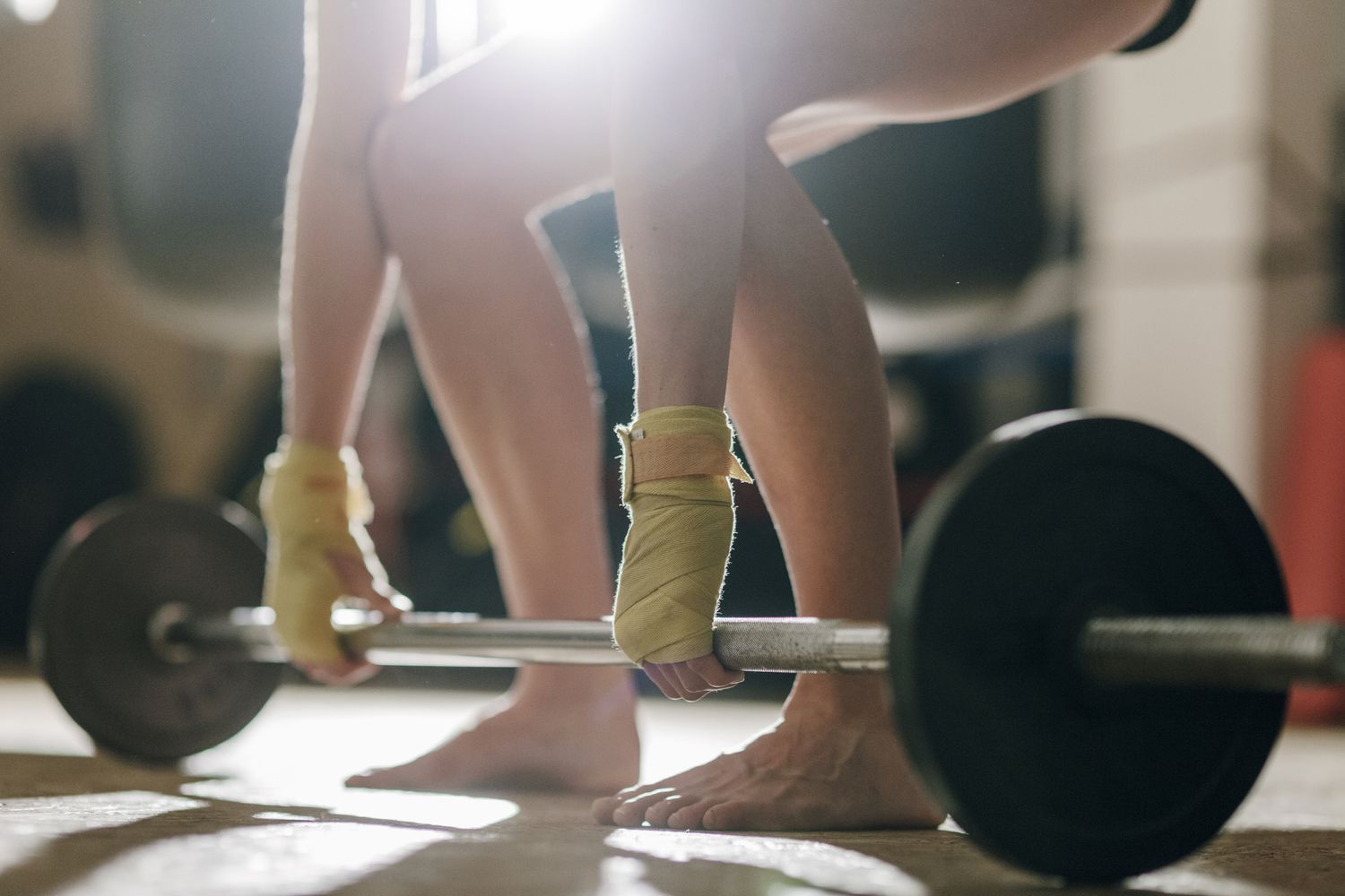 A low-angle view of a weightlifter preparing to lift a barbell.