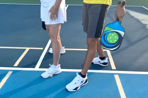 Two pickleball players standing on a blue court in full athletic gear holding paddles.