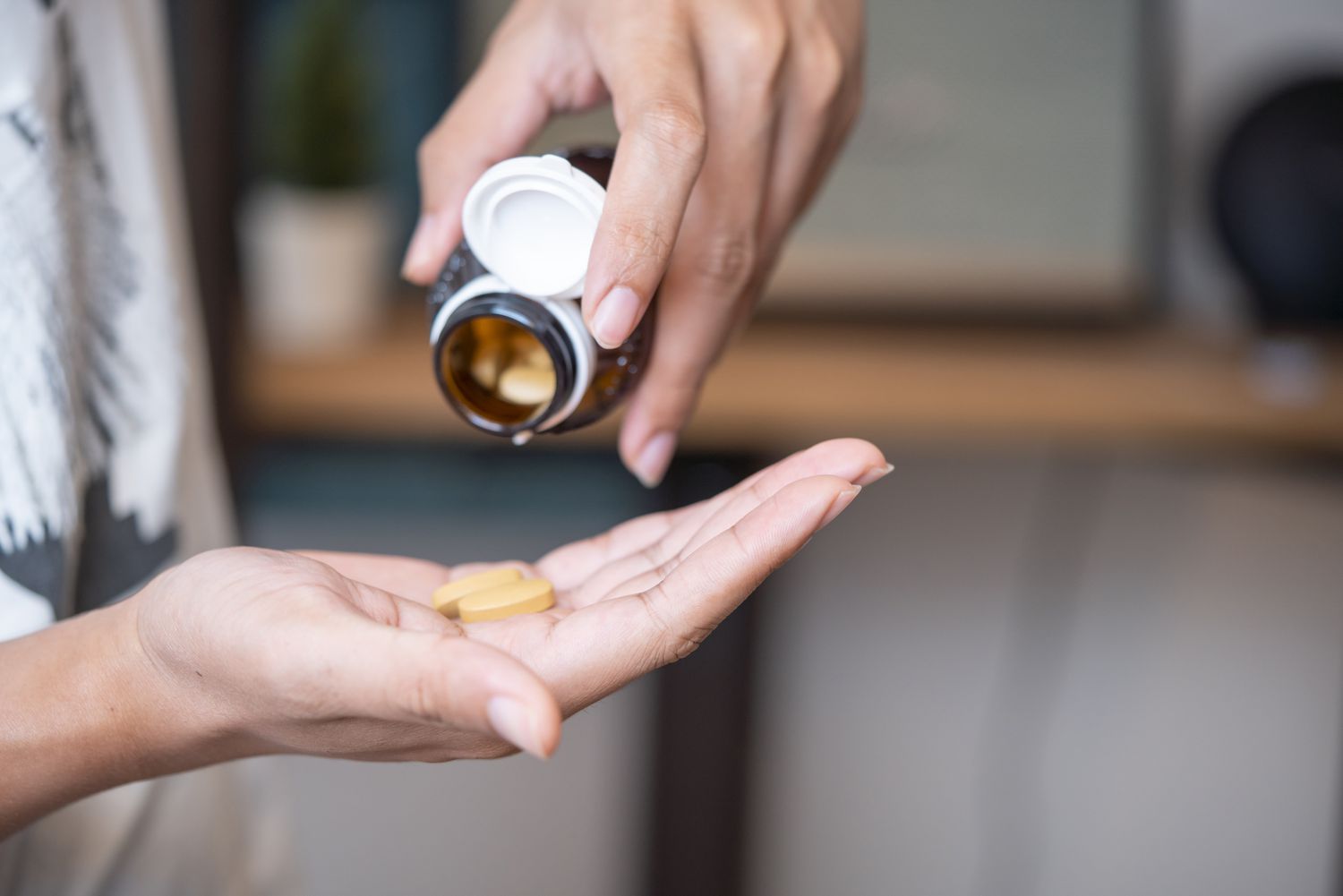 Close-up of a person pouring round vitamin tablets into their hand.