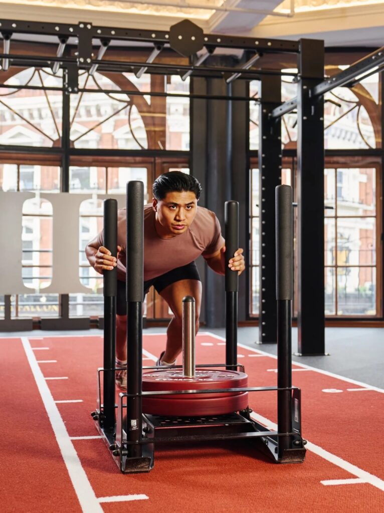 An athlete transitioning between the functional workout area and the running track during a Hyrox race.