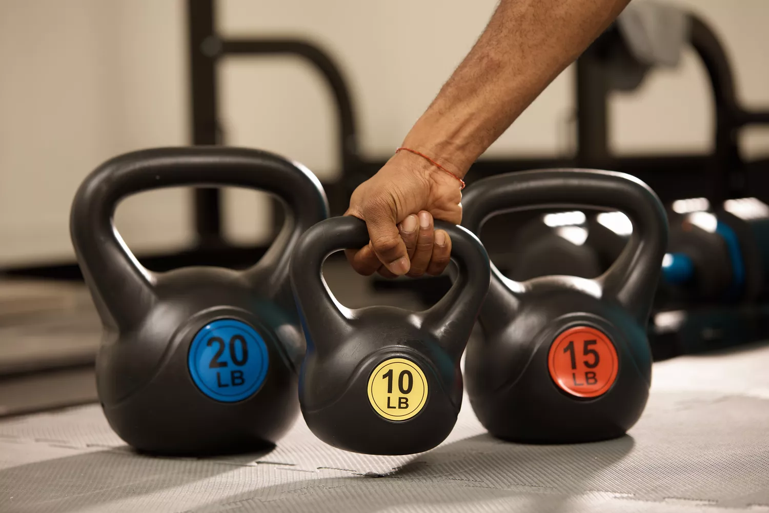 A set of three kettlebells weighing 10, 15, and 20 pounds on a gym mat.