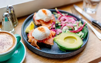 A healthy breakfast plate with poached eggs, smoked salmon, and avocado, focusing on high protein content.