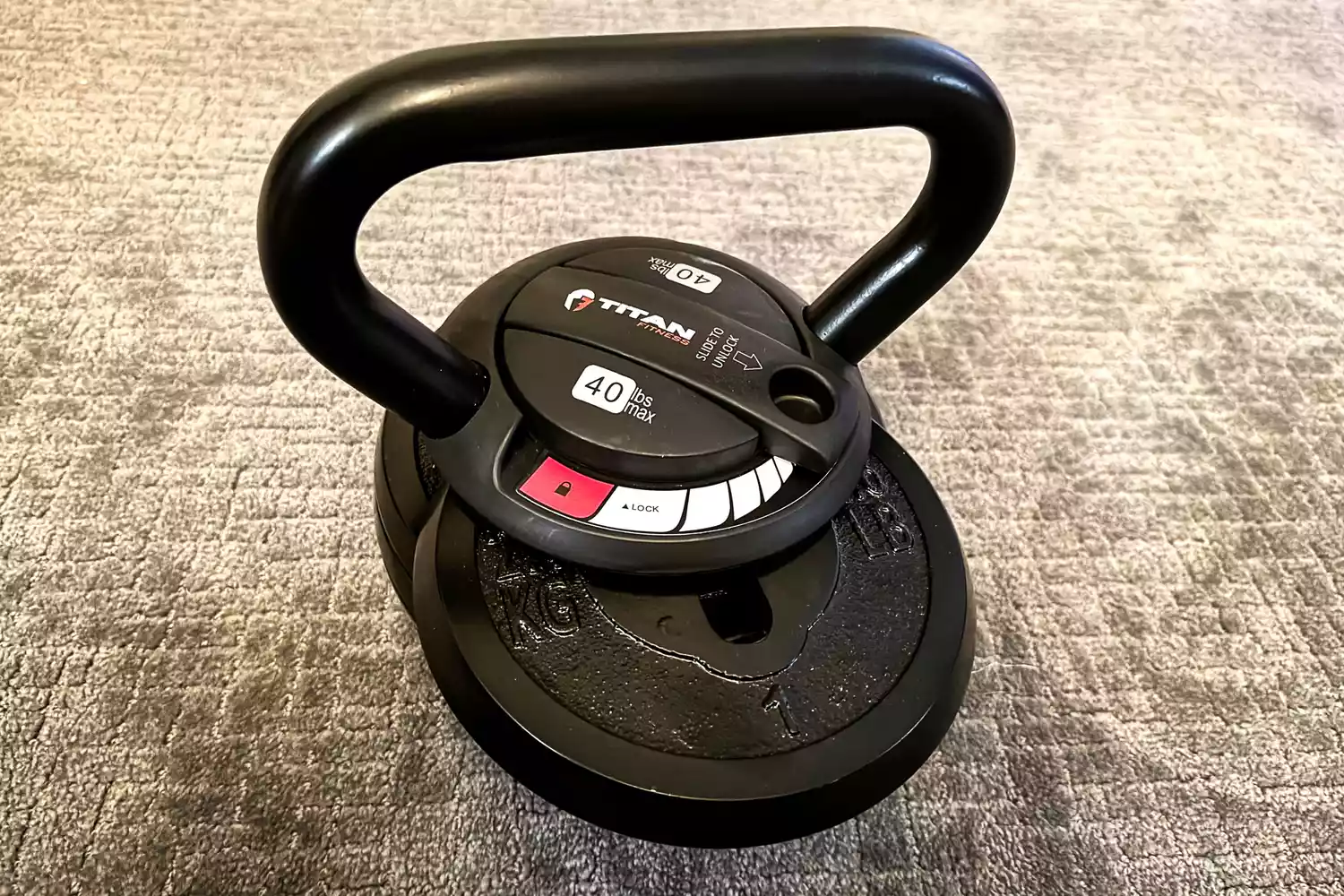 Close-up of a Titan Fitness adjustable kettlebell featuring a secure sliding lock mechanism.