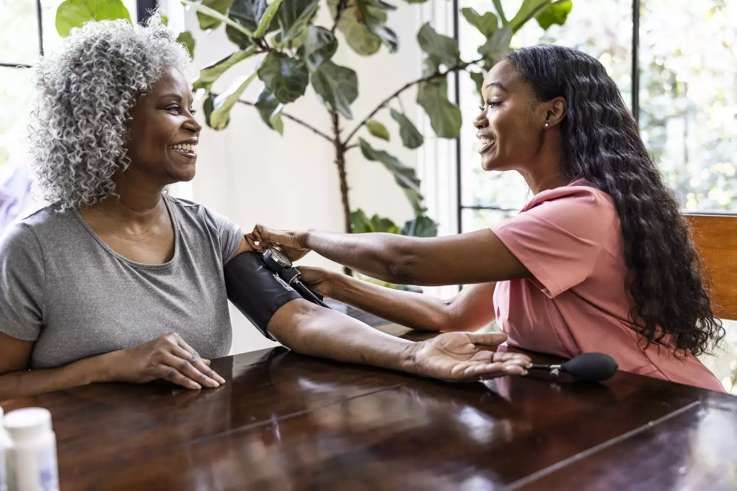 A healthcare professional using a blood pressure cuff on a patient's arm during a consultation.