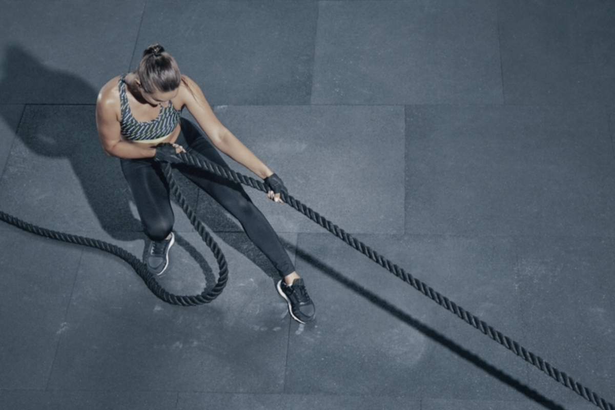 Participants competing in a large indoor arena with visible Hyrox branding and functional workout zones.
