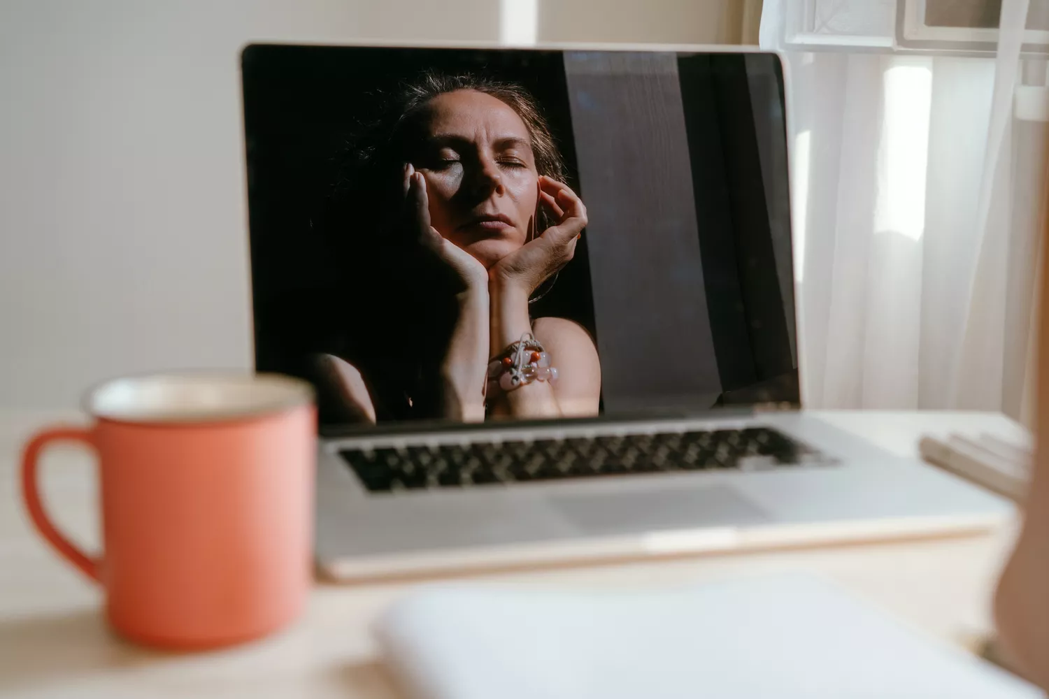 A woman sitting thoughtfully at her desk with a notebook, planning her fitness and nutrition strategy.