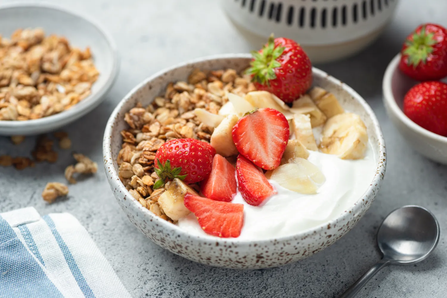 A bowl of yogurt topped with granola, strawberries, and bananas.