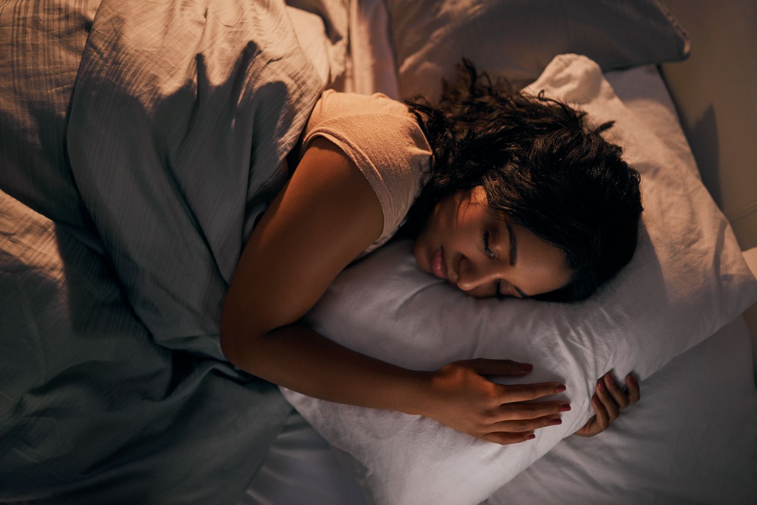 High angle shot of a young woman sleeping in bed, looking comfortable and undisturbed.
