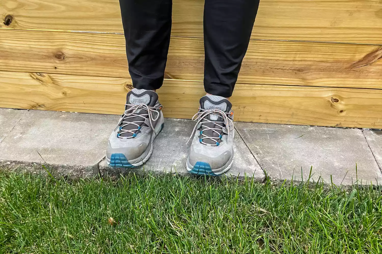 A person standing on outdoor concrete steps wearing Hoka Kaha 2 Low GTX hiking shoes.
